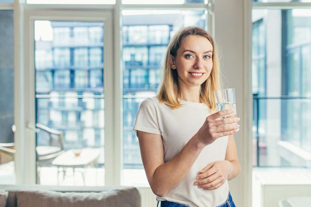 Woman in a Long Island home holding a glass of filtered water after EcoWater drinking water filtration