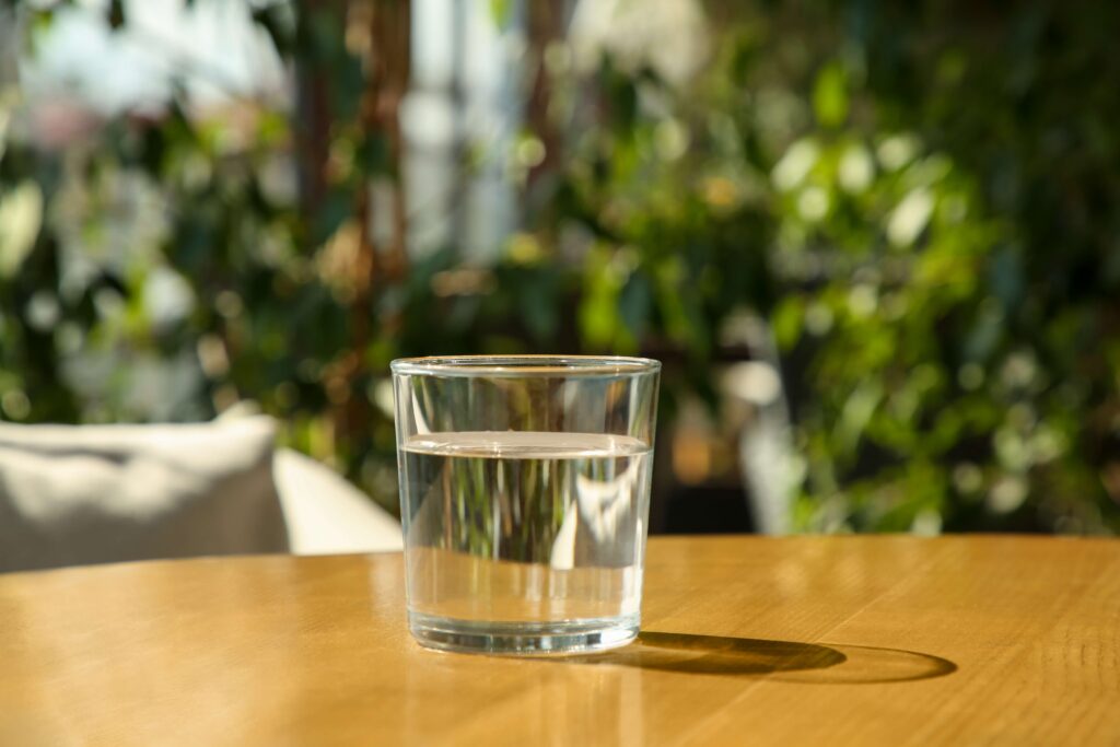 A clear glass of clean water resting on a wooden table.