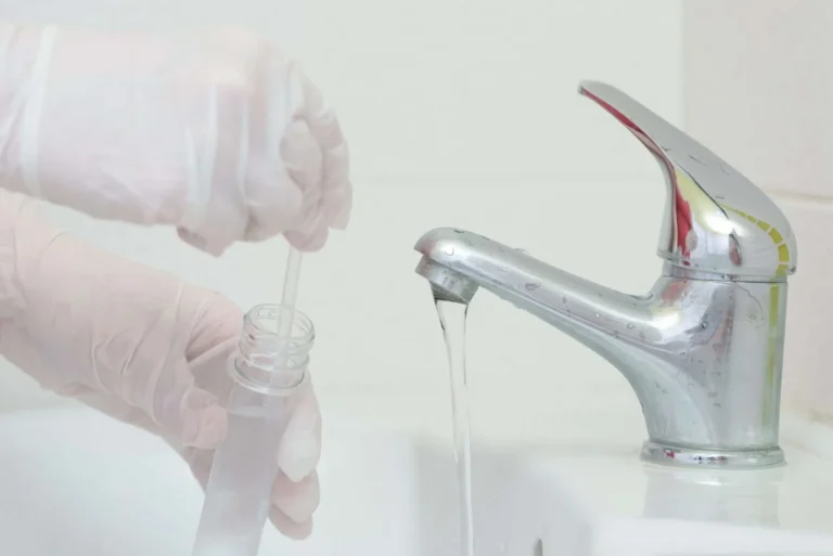 running faucet with gloved hands holding test tube