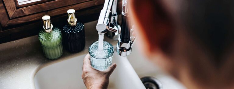 overflowing glass of water being filled from a sink